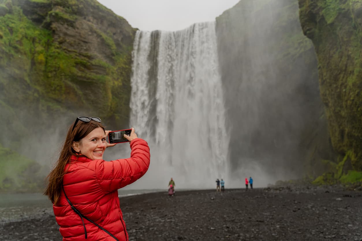 Mädchen fotografiert einen großen Wasserfall. Island